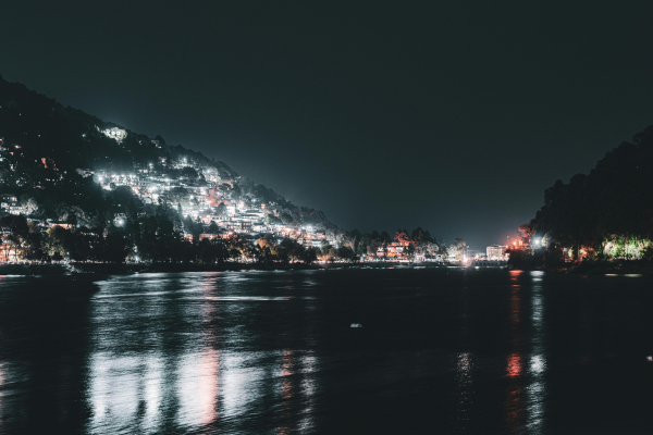 A photo of reflections of buildings and lights in the lake in the evening.