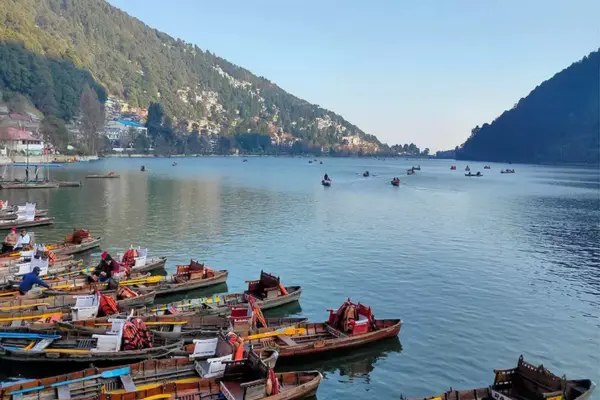 Photo of Naini Lake in the morning — sunlight reflecting on the water, boats lined up.